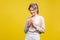 Portrait of smart cunning young woman with fair hair in casual beige blouse, isolated on yellow background