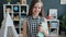 Portrait of smart girl standing in cozy room holding book and smiling looking at camera