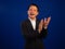 Portrait of smart middle-aged asian confident successful businessman wearing suit applauding to camera on blue background in