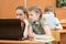Portrait of smart schoolgirls and schoolboy looking at the laptops in classroom