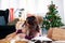 Portrait of smile woman sitting and kiss her lovely brown Akita dog in the living room which decorated with the Christmas theme