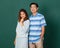 Portrait of a smiley happy loving Asian couple dressed casually standing relaxedly, smiling to a camera for studio shot over green