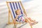 Portrait of smiling adorable blondy baby girl in dress or toddler child relaxing on a sunbed or a deckchair in the city park recre