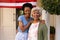 Portrait of smiling african american daughter with arm around mother at house entrance