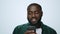 Portrait of smiling african american man using smartphone on grey background.