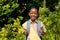 Portrait of smiling african american scout girl in uniform with backpack against plants