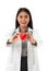 Portrait of smiling asian female cardiologist with stethoscope holding red heart shape model