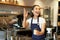 Portrait of smiling asian girl barista, giving out order in cafe, inviting guest to pick up takeaway order near counter