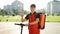 Portrait smiling asian man courier food delivery standing with thermal backpack, electric scooter looking at camera and