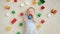 Portrait of smiling baby boy surrounded with lots of toys lying on carpet in playroom. Concept of children development