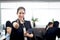 Portrait of smiling beautiful Asian woman officer hold tablet and give thumb up, standing at office with blurred busy working