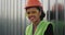 Portrait of a smiling beautiful engineer smiling large on the construction site wearing a orange helmet and yellow