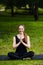 Portrait of smiling beautiful sporty young woman working out in park alley, standing with palms touching in Namaste