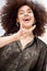 Portrait of smiling beautiful trendy mixed race woman with afro making cool hand gesture to pose alone outside. Below