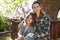 Portrait of smiling beautiful woman sitting with daughter on wooden bench