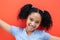 Portrait of smiling biracial elementary schoolgirl against orange background