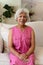 Portrait of smiling biracial mature woman with gray hair sitting on sofa at home