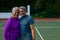 Portrait of smiling biracial senior couple embracing while standing in tennis court