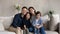 Portrait of smiling bonding parents and kids sitting on sofa.