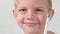 Portrait smiling boy with electric toothbrush. Close up funny face kid child boy brushing teeth on white brick