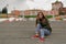 Portrait of smiling brunette woman on concrete steps in urban landscape, perspective effect, rule of thirds