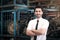 Portrait of smiling businessman seller standing with arms crossed at auto spare parts store shop warehouse with many second hand