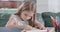 Portrait of smiling caucasian child doing homework at the table at home. Thoughtful schoolgirl solving math problems