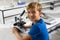 Portrait of smiling caucasian elementary schoolboy with microscope sitting at desk in laboratory
