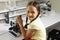 Portrait of smiling caucasian elementary schoolgirl with microscope sitting at desk in laboratory
