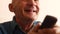 Portrait of smiling Caucasian grandfather watching TV. An elderly man 70 years older watches TV programs while holding a remote co