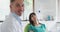 Portrait of smiling caucasian male dentist with female patient at modern dental clinic