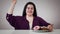 Portrait of smiling Caucasian obese girl sitting in front of sweets and measure tape. Fat woman moving aside tape meter