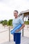 Portrait of smiling caucasian senior man with blue exercise mat standing at tourist resort