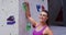 Portrait of smiling caucasian woman grabbing a hold on a climbing wall at indoor climbing wall