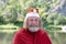 Portrait of a smiling charismatic adult man with a beard dressed as Santa Claus in nature background