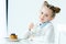 portrait of smiling child with glass of milk in hand and homemade pancakes with honey and berries