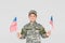 portrait of smiling child in military uniform with american flagpoles in hands