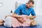 portrait of smiling chiropractor massaging back of patient that lying on massage table