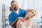 portrait of smiling chiropractor stretching neck of woman