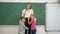 Portrait of smiling classroom teacher hugging with learners children near blackboard
