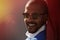 Portrait of smiling confident young African-American businessman in formal wear and sun glasses in city park.Blurred