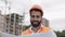 Portrait of smiling construction worker in orange helmet looking at the camera. The builder with construction project