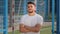 Portrait of smiling contented young sportsman in summer sportswear standing at stadium satisfied with results of game