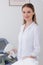 portrait of smiling cosmetologist in white coat with laser hair removal apparatus