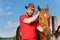 Portrait of smiling cowboy with his bay horse