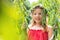 Portrait of smiling cute girl in red dress standing amidst leaves at park