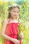 Portrait of smiling cute girl in red dress standing amidst leaves at park