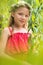 Portrait of smiling cute girl in red dress standing amidst leaves at park