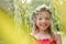 Portrait of smiling cute girl wearing flowers standing amidst leaves at park