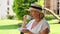 Portrait of smiling cute mature female relaxing in her garden with hot drink coffee in morning on a sunny day. Concept